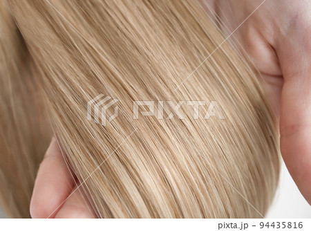 A strand of blond hair on a white background. Close-up. 94435816