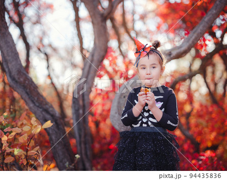 Young girl in black costume goes trick or treating Young girl in black costume goes trick or treating 94435836