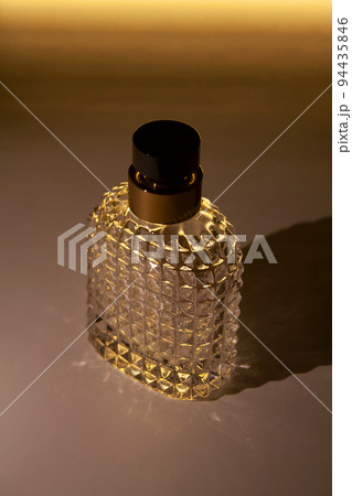 Textured glass perfume bottle isolated with glowing illumination on the background 94435846