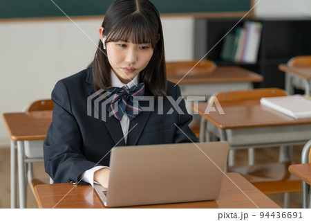 学校の教室でノートパソコンを使って勉強する女子高生 94436691