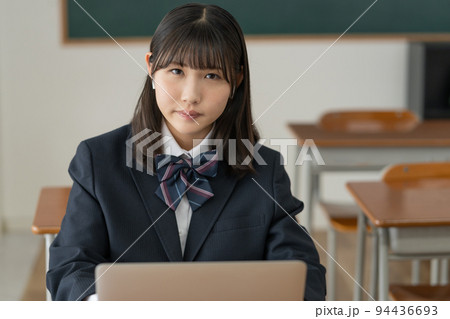 学校の教室でノートパソコンを使って勉強する女子高生 94436693