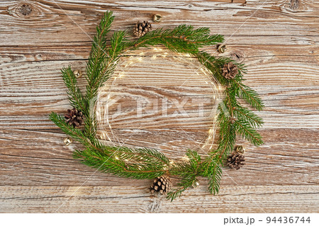 Christmas circle composition with fir tree branches and lighting garland on wooden background. Christmas frame, flat lay. Xmas greeting banner with copy space 94436744