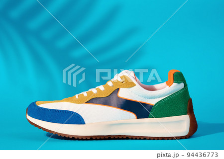 Stylish colorful shoes on blue background with plant shadows, Trendy sneakers, Stylish fashionable minimalism concept 94436773