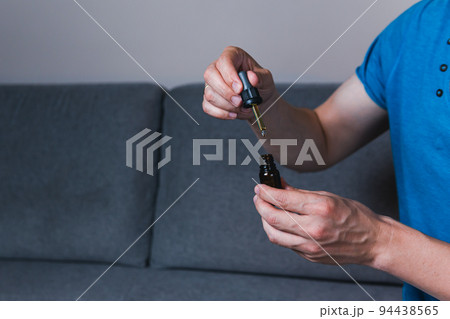 Adult man using and holding medical cannabis oil. CBD 94438565
