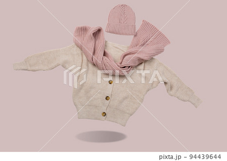 Beige sweater with buttons, pink scarf and hat, as if levitating, casting a shadow, concept Beige sweater with buttons, pink scarf and hat, as if levitating, casting a shadow, concept 94439644