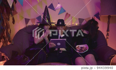 A group of friends is watching a creepy Halloween movie on a tablet. Fright A group of friends is watching a creepy Halloween movie on a tablet. Fright 94439940
