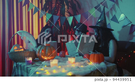 A group of friends will find out how many candies are in paper bags. Friends celebrate Halloween by laughing and chatting together A group of friends will find out how many candies are in paper bags. Friends celebrate Halloween by laughing and chatting together 94439951