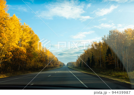 Autumn landscape from behind the car glass. The road going into the distance. Front view. 94439987