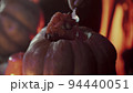 Close-up of a girl's hand taking the pulp out of a pumpkin for Halloween 94440051