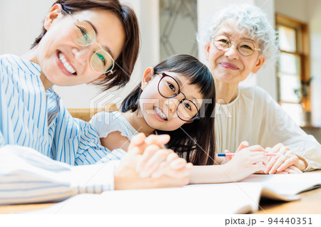 勉強する小学生の女の子を見守る家族 勉強する小学生の女の子を見守る家族 94440351