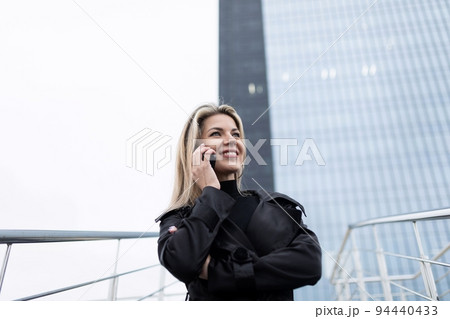 middle-aged businesswoman conducts a business conversation against the backdrop of a multi-storey 94440433