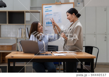 Happy business asian people are keeping arms raised hi five and expressing joyful while standing. achieving goals. Happy business asian people are keeping arms raised hi five and expressing joyful while standing. achieving goals. 94440537