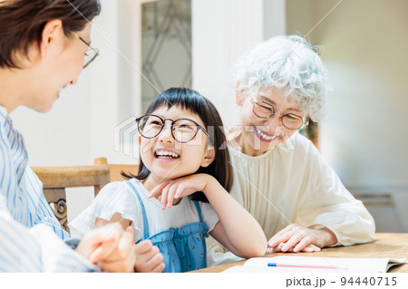 勉強する小学生の女の子を見守る家族 94440715