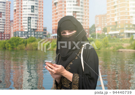 A Muslim woman in a national outfit walks around an unfamiliar European city after emigrating 94440739