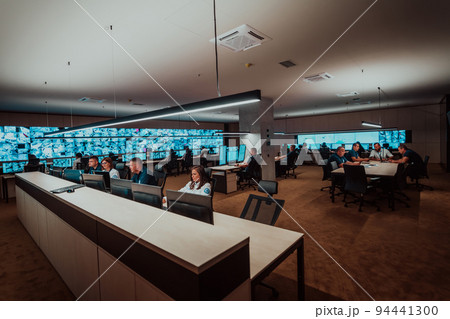 Group of Security data center operators working in a CCTV monitoring room looking on multiple monitors Officers Monitoring Multiple Screens for Suspicious Activities Team working on the System Contr Group of Security data center operators working in a CCTV monitoring room looking on multiple monitors Officers Monitoring Multiple Screens for Suspicious Activities Team working on the System Contr 94441300