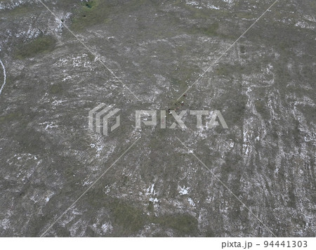 Aerial shot of meadows covered with soft mist on a cloudy day in the countryside. Aerial scenic candid authentic rural view  94441303