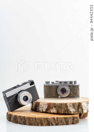 Two retro photo cameras on wooden boards. Concept of mens and womens cameras. Vertical shot isolated on white. 94442355