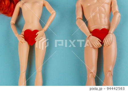 Naked male and female dolls holding red hearts covering thier groin. Love or valentines day concept. Blue background with copy space. Naked male and female dolls holding red hearts covering thier groin. Love or valentines day concept. Blue background with copy space. 94442563
