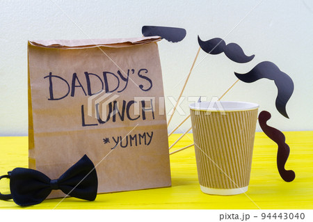 Paper bag with bow tie and disposable cup. Daddys lunch concept. Paper bag with bow tie and disposable cup. Daddys lunch concept. 94443040