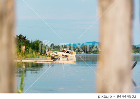 Old rusty boat aground on the shore of the river bay. Human pollution by industrial waste Old rusty boat aground on the shore of the river bay. Human pollution by industrial waste 94444902
