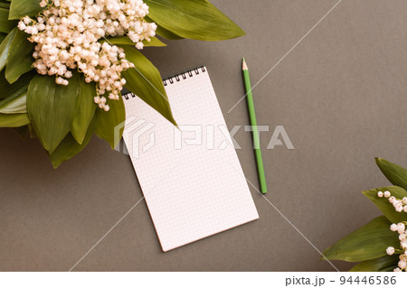 Blank notebook, pencil and bouquets of lilies of the valley on a green background. Top view. Planning, goal setting, wishlist. Spring update Blank notebook, pencil and bouquets of lilies of the valley on a green background. Top view. Planning, goal setting, wishlist. Spring update 94446586