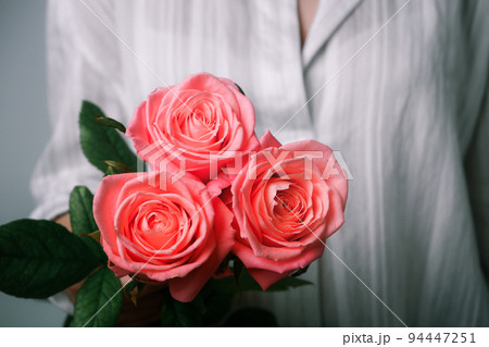 Female hands with flower. Woman in white shirt holding tender pink Rose Flower in Hands. Close up view on flower. 94447251