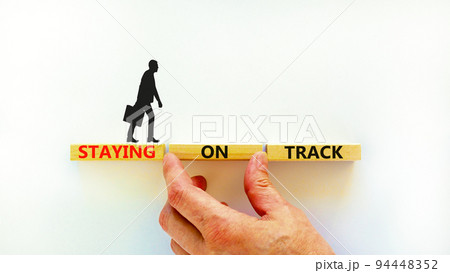 Staying on track symbol. Concept words Staying on track on wooden blocks on a beautiful white background. Businessman hand. Business, motivational and staying on track concept. Copy space. Staying on track symbol. Concept words Staying on track on wooden blocks on a beautiful white background. Businessman hand. Business, motivational and staying on track concept. Copy space. 94448352