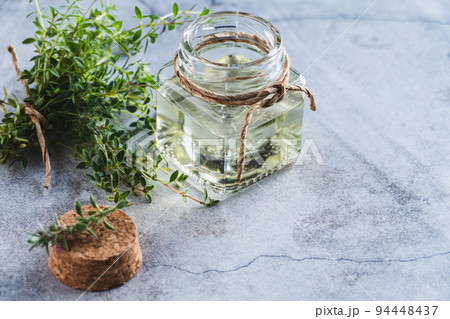 Thyme oil in a bottle, Thymus green leaves on gray background 94448437