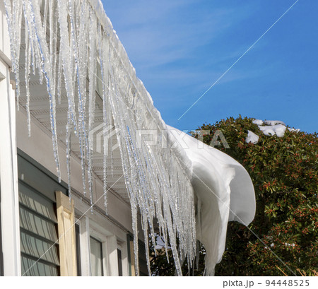 Icicles hanging from roof of a house as the snow is melting Icicles hanging from roof of a house as the snow is melting 94448525