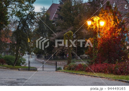 empty street in autumn. urban morning with lanterns. colorful foliage on the ground. red ivy plant on the wall 94449165