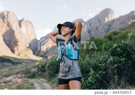 Laughing woman in sportswear relaxing during hike. Smiling female in wild terrain looking away.	 94450957