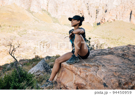 Smiling woman hiker sitting on big stone in valley enjoying the view	 94450959