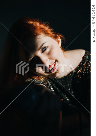 Portrait of redhead female singer woman in sparkly evening dress holding microphone. Singer at microphone. Woman singing and holding mic. Female vocal talent. Music show recital. 94451414