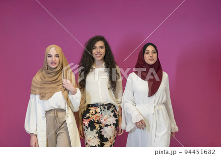 three Muslim women in hijab in a modern clothes pose against a pink background three Muslim women in hijab in a modern clothes pose against a pink background 94451682