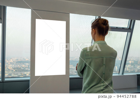 Woman looking at blank interactive touchscreen white display of electronic kiosk 94452788