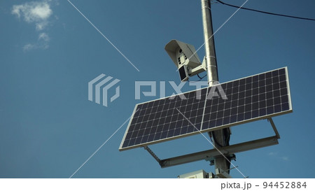 Photo camera monitors the rules of the road. Camera on a pole with a solar panel against the sky. 94452884