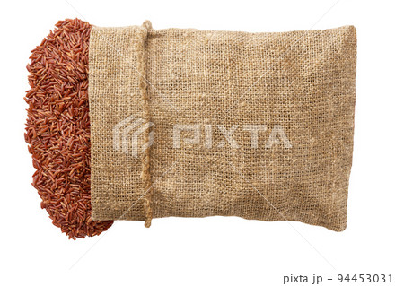 Grains are scattered out of the bag top view. red rice in sack isolated on white background flat lay. 94453031