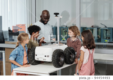 Group of clever intercultural pupils and their teacher of robotics using tablet 94454493