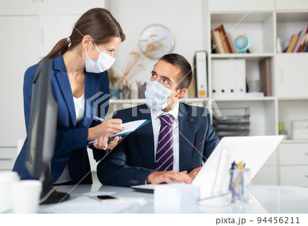 Manager in protective medical mask gives task to assistant 94456211
