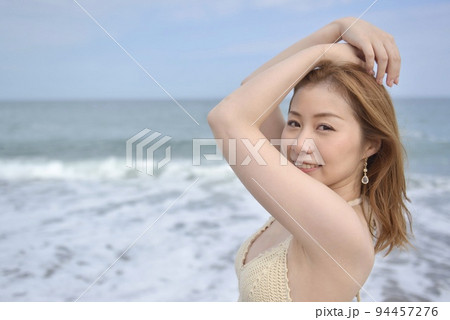 海岸でポーズをとるビキニの水着を着た若い女性 94457276