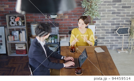 インダストリアルなオフィスで打ち合わせする男女 94459514