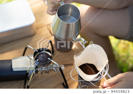 屋外でコーヒーをハンドドリップする様子 94459823