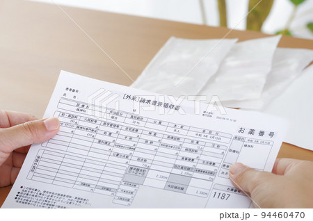 医療費の請求書を見つめる女性 94460470