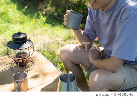 屋外でドリンクを手にリラックスする男性の様子 94460646