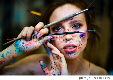 Portrait of a woman artist with a drops of paints on the face and hands. Portrait of a woman artist with a drops of paints on the face and hands. 94461319