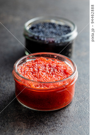 Red and black caviar in jar on dark table. Red and black caviar in jar on dark table. 94462888