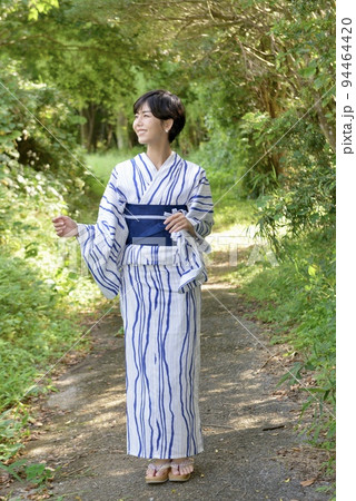 緑の森林を背景にポーズをとる浴衣を着た若い女性 緑の森林を背景にポーズをとる浴衣を着た若い女性 94464420