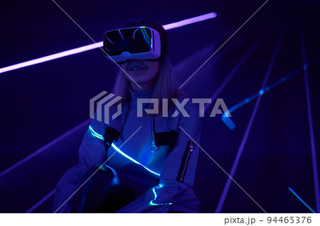 Woman is using virtual reality headset to access in metaverse. Woman is using virtual reality headset to access in metaverse. 94465376