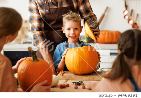 Happy boy smiling at camera while helping dad carve Halloween pumpkin. Happy boy smiling at camera while helping dad carve Halloween pumpkin. 94469391