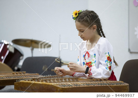 The girl plays the ethnic instrument dulcimer The girl plays the ethnic instrument dulcimer 94469937